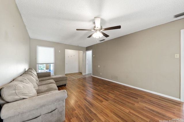 living room with ceiling fan, dark hardwood / wood-style floors, and a textured ceiling