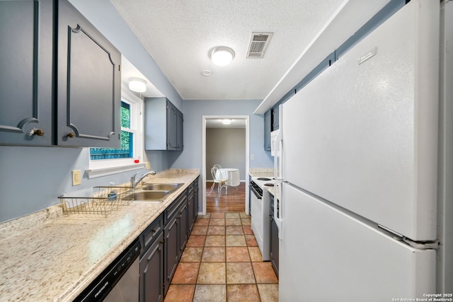 kitchen with light tile patterned floors, white appliances, sink, and a textured ceiling