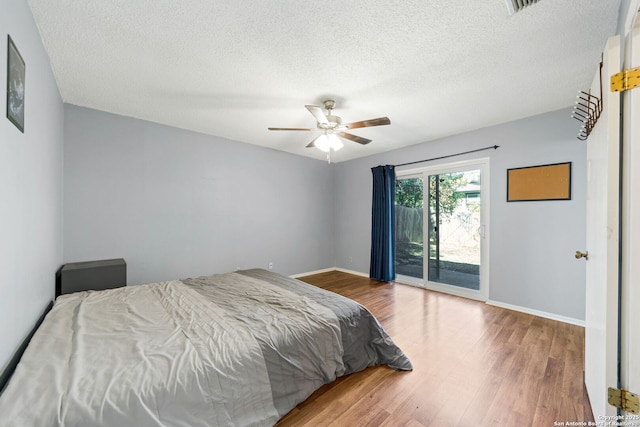 bedroom featuring hardwood / wood-style flooring, access to outside, a textured ceiling, and ceiling fan