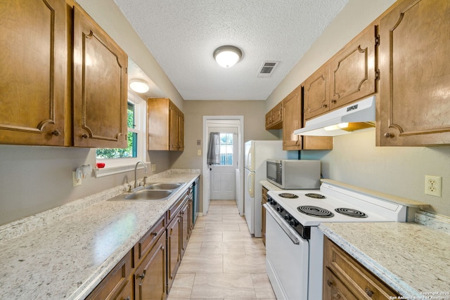 kitchen with sink, light stone counters, a textured ceiling, light tile patterned floors, and white appliances