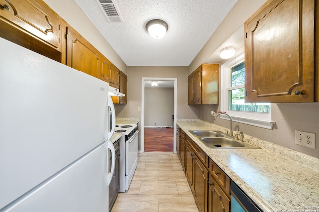 kitchen featuring sink, white appliances, light tile patterned floors, and a textured ceiling