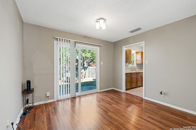 spare room with sink, light hardwood / wood-style flooring, and a textured ceiling