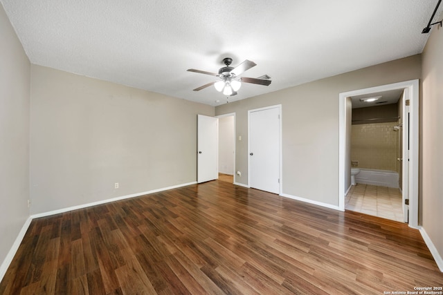 unfurnished bedroom featuring ceiling fan, connected bathroom, hardwood / wood-style floors, and a textured ceiling