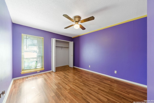 unfurnished bedroom with hardwood / wood-style flooring, a textured ceiling, ceiling fan, and a closet