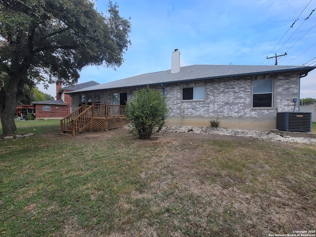 rear view of house with cooling unit, a lawn, and a deck