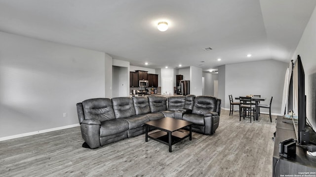 living room featuring lofted ceiling and light hardwood / wood-style flooring