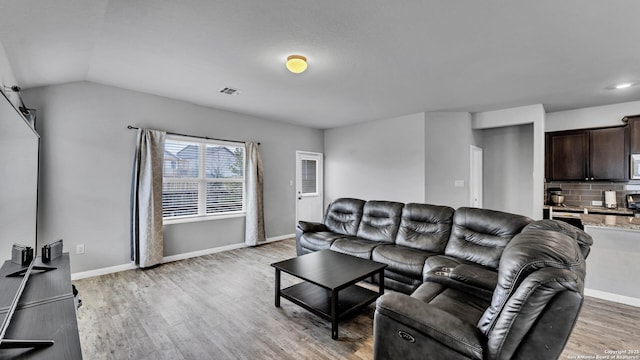 living room featuring lofted ceiling and light hardwood / wood-style flooring