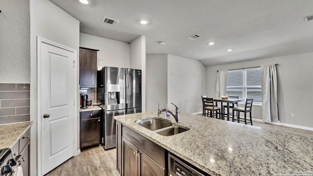 kitchen featuring sink, light hardwood / wood-style floors, stainless steel appliances, light stone countertops, and dark brown cabinets