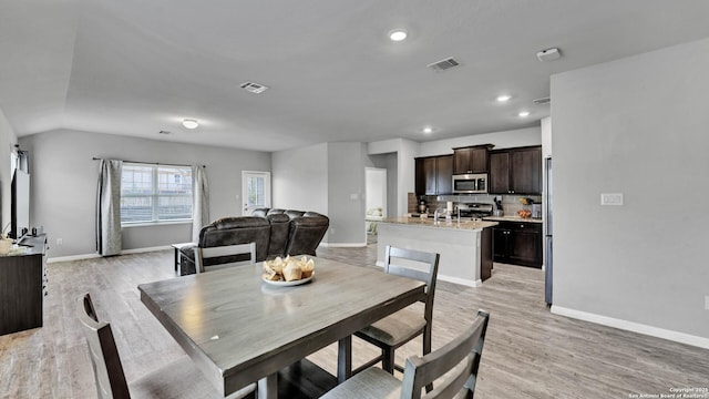 dining space with vaulted ceiling and light wood-type flooring