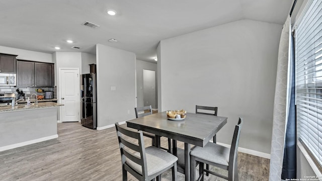 dining space with lofted ceiling and light hardwood / wood-style floors