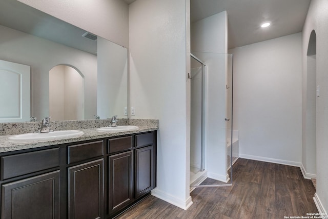 bathroom with hardwood / wood-style flooring, vanity, and walk in shower