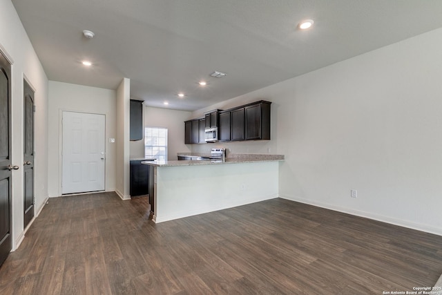 kitchen featuring dark hardwood / wood-style floors, light stone countertops, kitchen peninsula, and appliances with stainless steel finishes