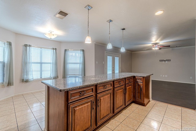 kitchen with pendant lighting, light tile patterned floors, light stone countertops, and french doors