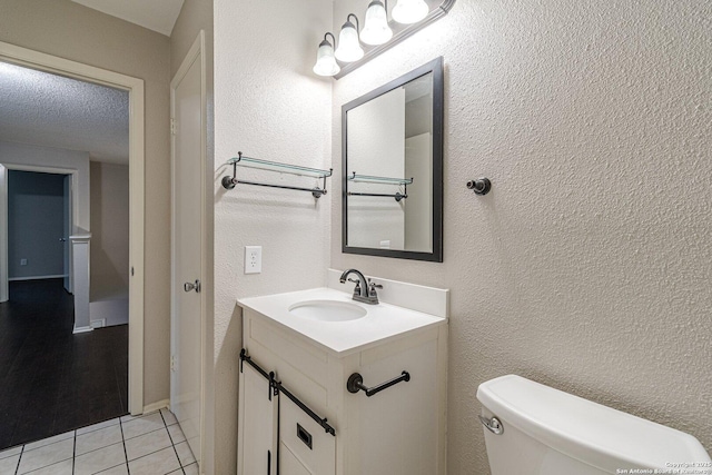 bathroom with vanity, toilet, tile patterned flooring, and a textured ceiling