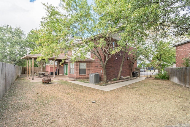 back of property with a yard, cooling unit, and a fire pit