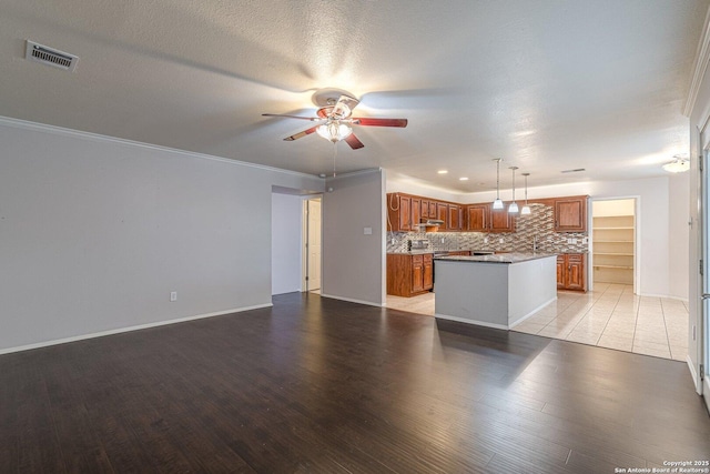 kitchen with light hardwood / wood-style flooring, ceiling fan, a kitchen island, decorative backsplash, and decorative light fixtures