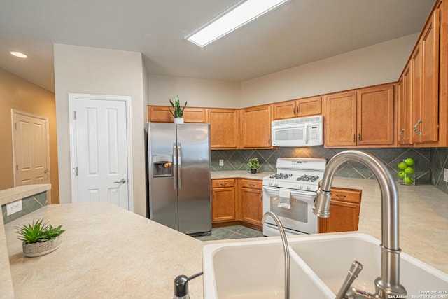 kitchen featuring white appliances, sink, and backsplash