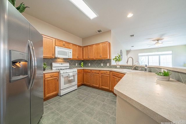 kitchen featuring sink, white appliances, ceiling fan, decorative backsplash, and kitchen peninsula