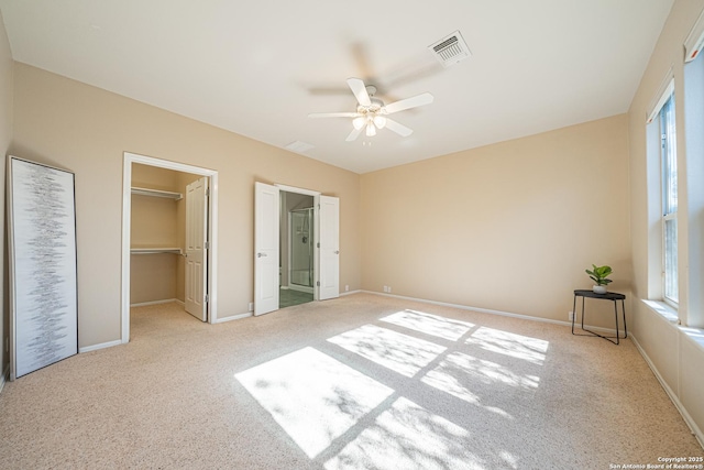 unfurnished bedroom with a walk in closet, light colored carpet, ceiling fan, and a closet