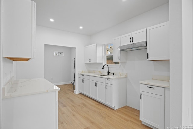 kitchen with light stone counters, sink, light hardwood / wood-style floors, and white cabinets