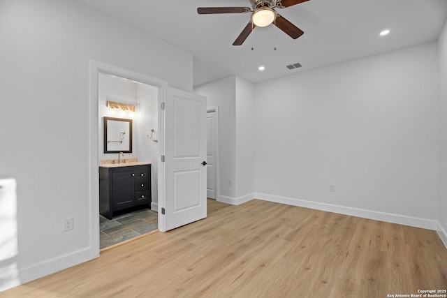 unfurnished bedroom featuring ensuite bath, sink, and light wood-type flooring