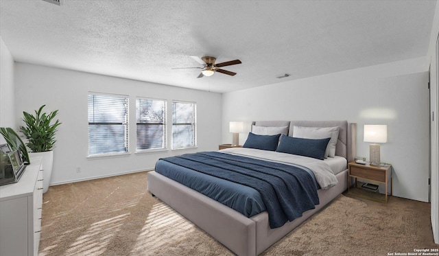 carpeted bedroom featuring ceiling fan and a textured ceiling