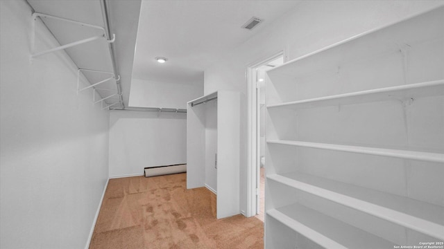 spacious closet featuring a baseboard radiator and light colored carpet