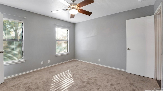 carpeted spare room featuring ceiling fan