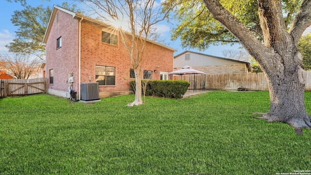 back of property with central AC unit and a lawn