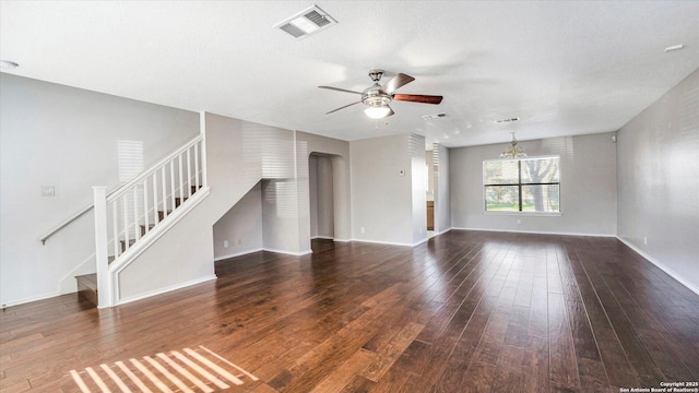 unfurnished living room with dark wood-type flooring, ceiling fan with notable chandelier, and a textured ceiling