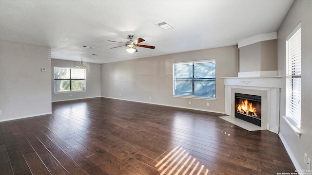 unfurnished living room with dark hardwood / wood-style floors and ceiling fan with notable chandelier