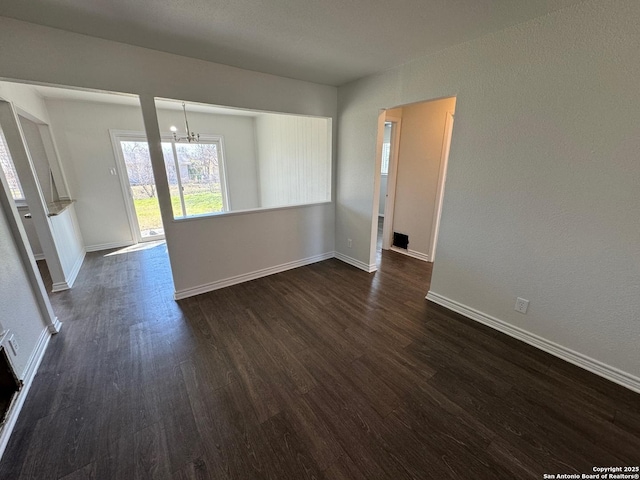 spare room with dark hardwood / wood-style floors and a notable chandelier