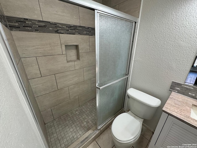 bathroom with walk in shower, vanity, toilet, and tile patterned flooring