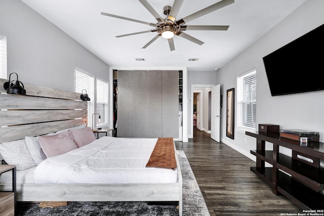 bedroom with ceiling fan, dark hardwood / wood-style floors, a closet, and multiple windows