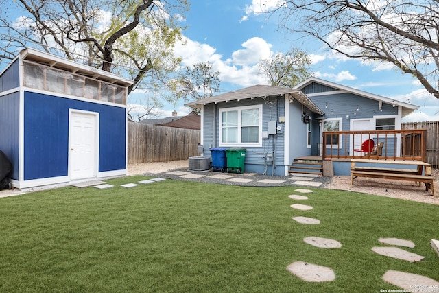 rear view of house with a yard, a deck, and a shed