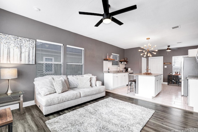 living room featuring ceiling fan with notable chandelier and hardwood / wood-style floors