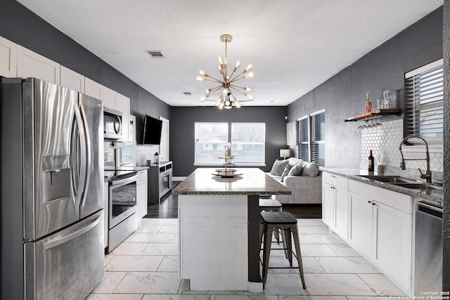 kitchen featuring sink, white cabinetry, a center island, a kitchen breakfast bar, and stainless steel appliances