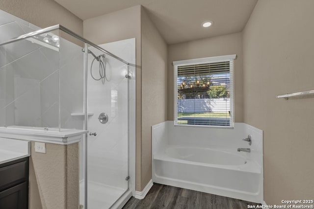 bathroom featuring hardwood / wood-style flooring, vanity, and plus walk in shower