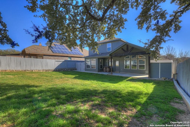 back of house with a lawn, a patio area, and solar panels