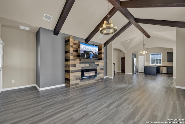 unfurnished living room featuring high vaulted ceiling, dark wood-type flooring, a chandelier, and a fireplace