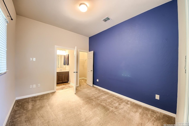 unfurnished bedroom featuring ensuite bathroom and light carpet