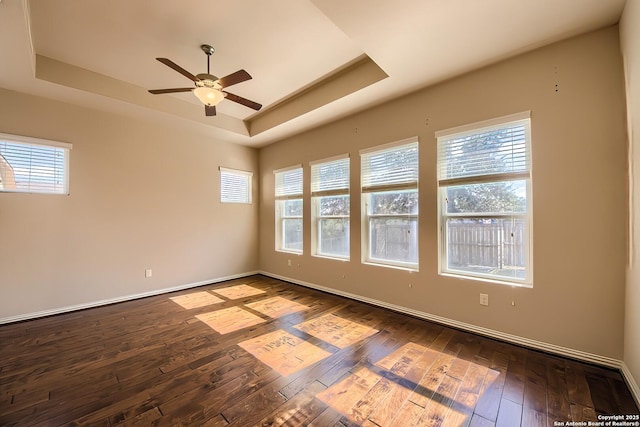 empty room featuring dark hardwood / wood-style floors, a raised ceiling, and ceiling fan