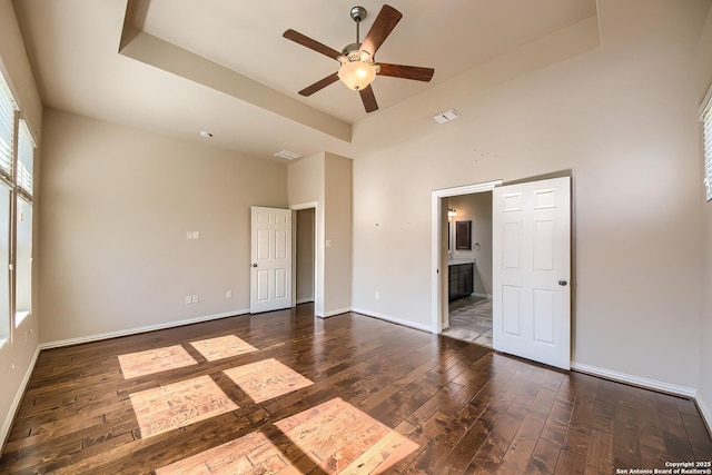 unfurnished room featuring dark hardwood / wood-style flooring, a raised ceiling, and ceiling fan