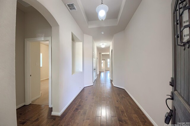 hall with dark wood-type flooring and a raised ceiling