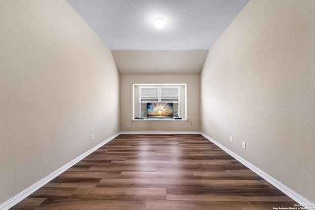 unfurnished room with dark hardwood / wood-style floors, vaulted ceiling, and a textured ceiling