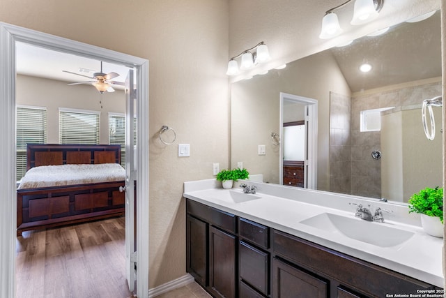 bathroom with vaulted ceiling, hardwood / wood-style floors, vanity, tiled shower, and ceiling fan