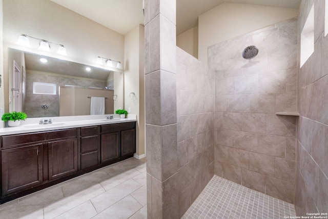 bathroom with tiled shower, vanity, and tile patterned flooring