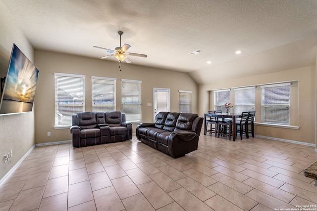 living room featuring ceiling fan, vaulted ceiling, and a textured ceiling