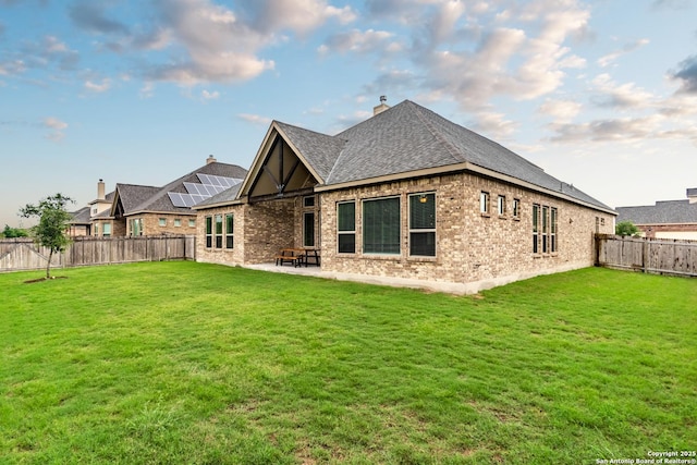 back of house with a yard, a patio, and solar panels