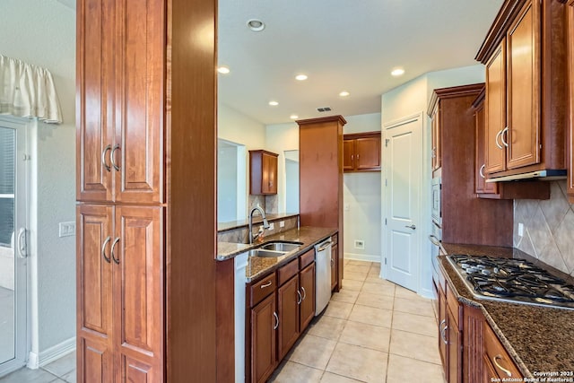 kitchen featuring appliances with stainless steel finishes, sink, decorative backsplash, and dark stone counters